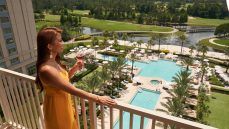 woman enjoying cocktail on balcony of her guestroom